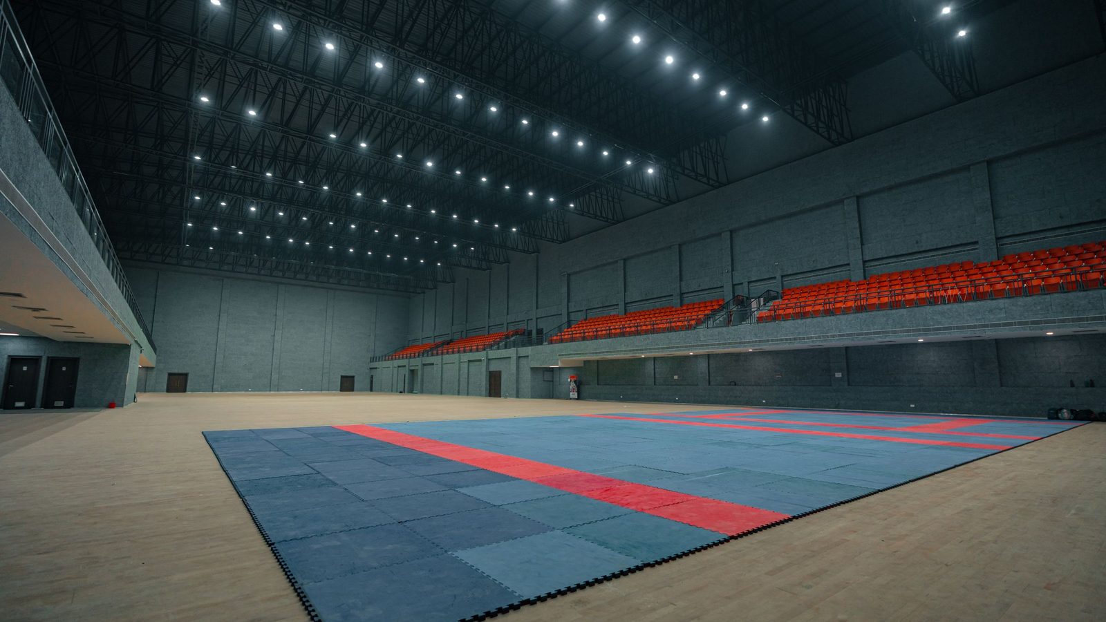 Spor salonunun açılıştan önceki hâli: zemine serilmiş müsabaka minderi, boş tribün ve tavan aydınlatması